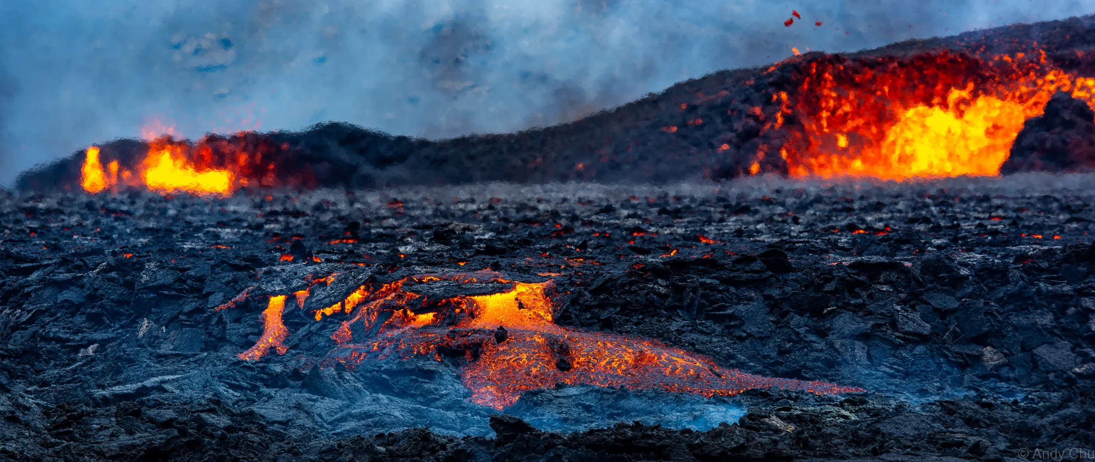 Glowing orange lava spreading across dark volcanic rock