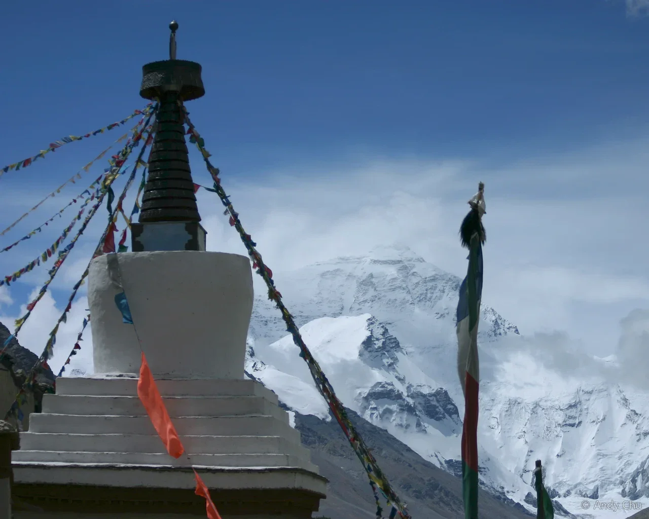 White stupa and prayer flags before a snowy mountain
