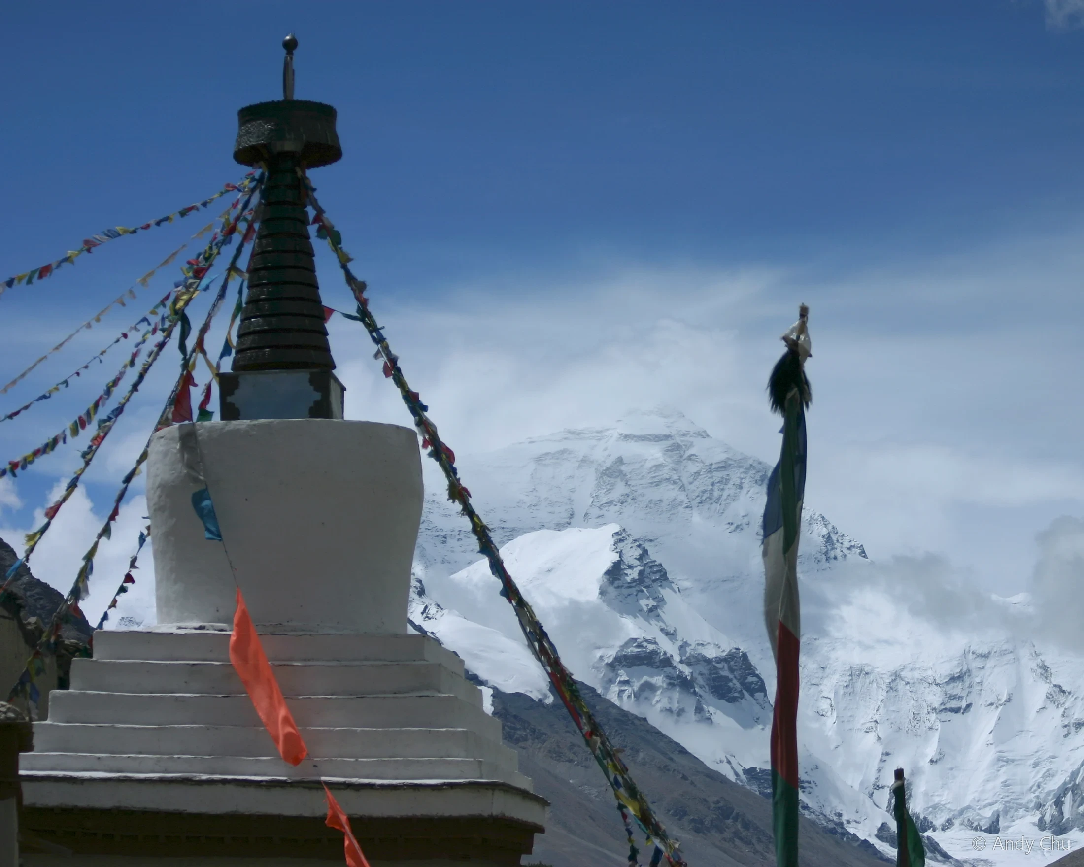 White stupa and prayer flags before a snowy mountain