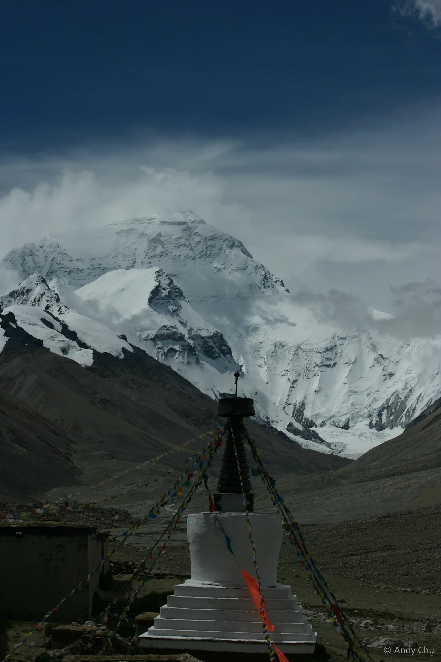 Snow-covered mountain rising beyond a stupa and prayer flags
