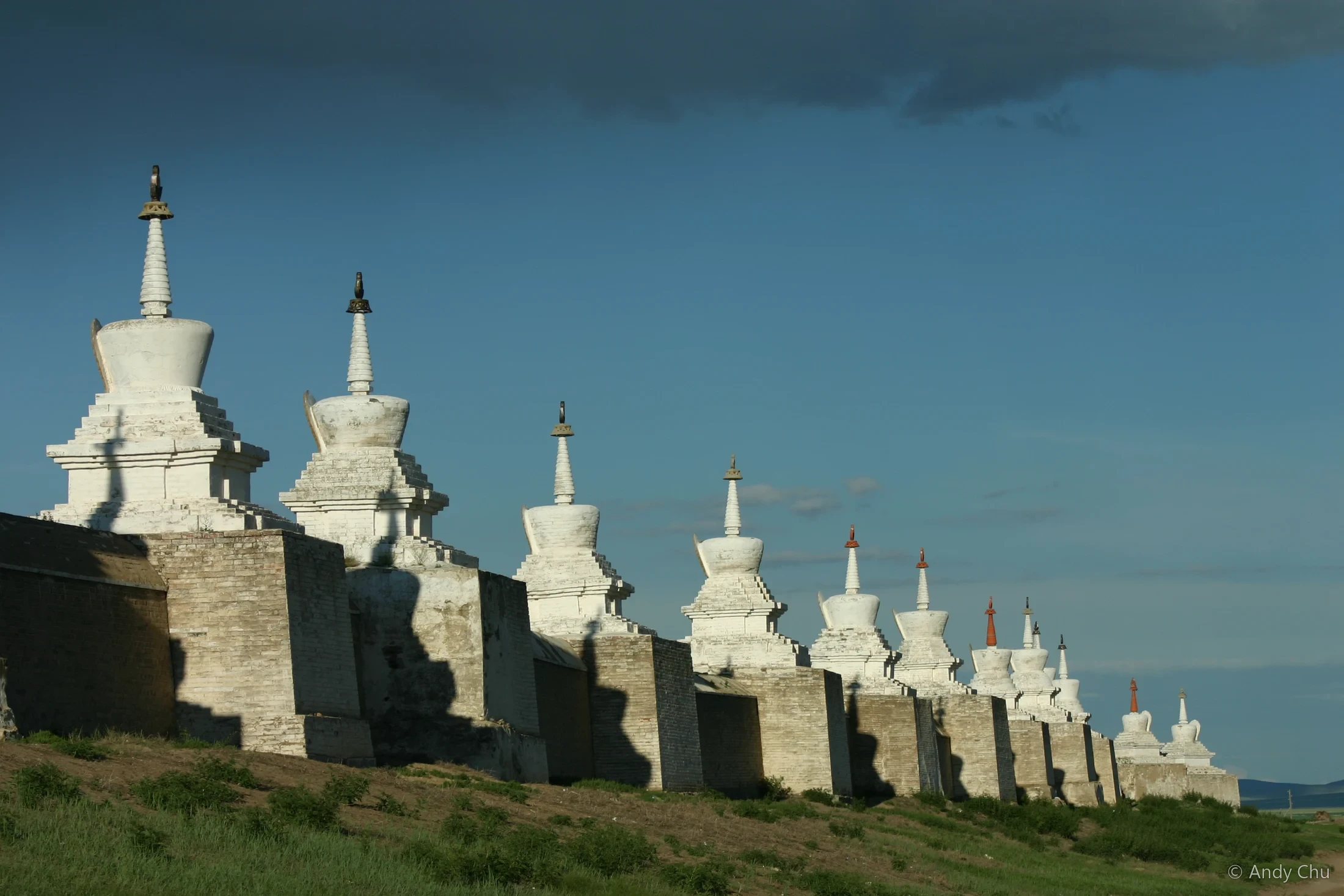 A row of white stupas beneath a blue sky